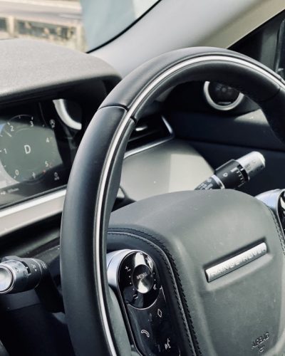 hands-of-a-man-on-the-steering-wheel-of-a-land-rover-range-rover-evoque-details-of-modern-interior_t20_gLoXP7